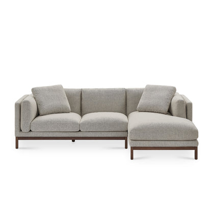 The Owen Chaise Sectional Sofa is a modern L-shaped sectional in gray, featuring plush cushions and low-profile wooden legs, set against a white background.