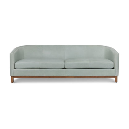 Introducing the Pippa Sofa in Mediterranean: a sleek, modern design with a light green hue and a wooden base. It boasts two large seat cushions and a curved backrest for an elegantly minimalistic look.