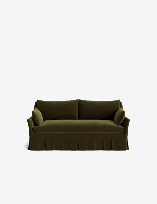 The Portola Pleated Sofa is a dark green piece with a stylish pleated skirt design. It features two seat cushions, two back cushions, and matching armrest cushions, all set against a plain white background.