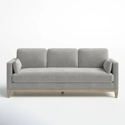 The Pera 84" Upholstered Sofa, showcasing a minimalist design in modern gray with three cushions and wooden legs, is set against a plain white background.