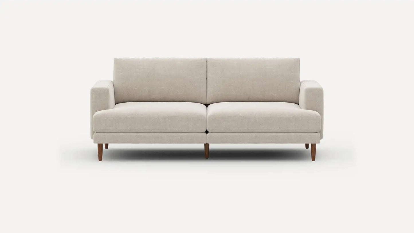 Introducing the Ember Mid-Century Modern 75" Sofa— a contemporary light beige piece showcasing clean lines and a minimalist design. This sofa features two seat cushions and two back cushions, complemented by low armrests and wooden legs, all set against a plain white background.