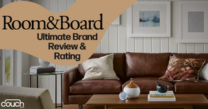A living room scene with a brown leather couch, two patterned pillows, a wooden coffee table with decorative items, and framed art on a white paneled wall. Text reads "Room&Board Ultimate Brand Review & Rating" with a logo for "couch.com" in the corner.