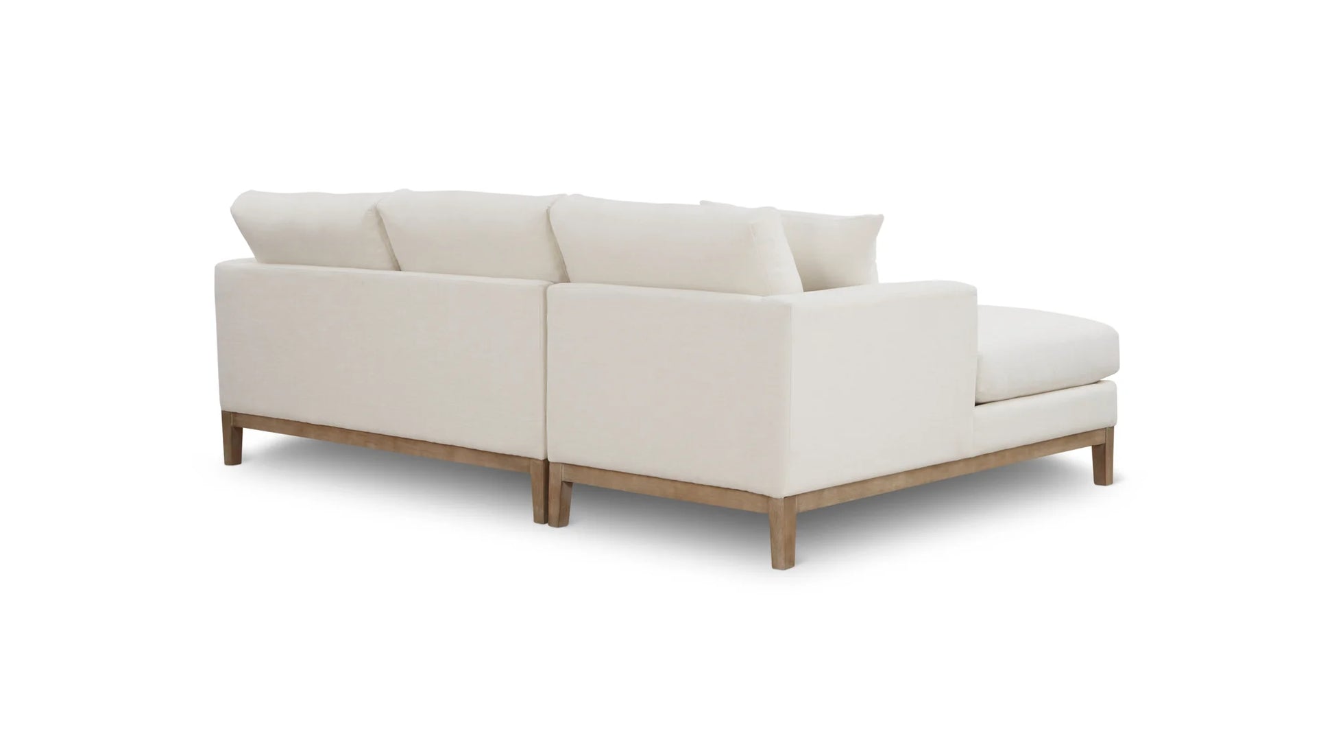 The Any Day Sectional is a white sectional sofa with a chaise lounge on the right side, featuring soft cushions and light wooden legs, positioned against a white background.