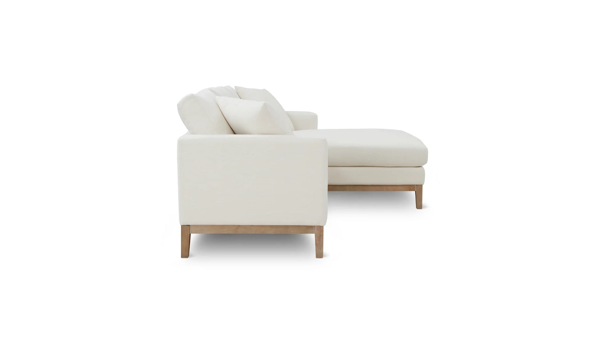 Side view of the Any Day Sectional, a modern white sectional sofa featuring plush cushions. It boasts light wooden legs and an L-shaped design with a right-extending chaise, perfectly suited for contemporary interiors with its minimalist style.