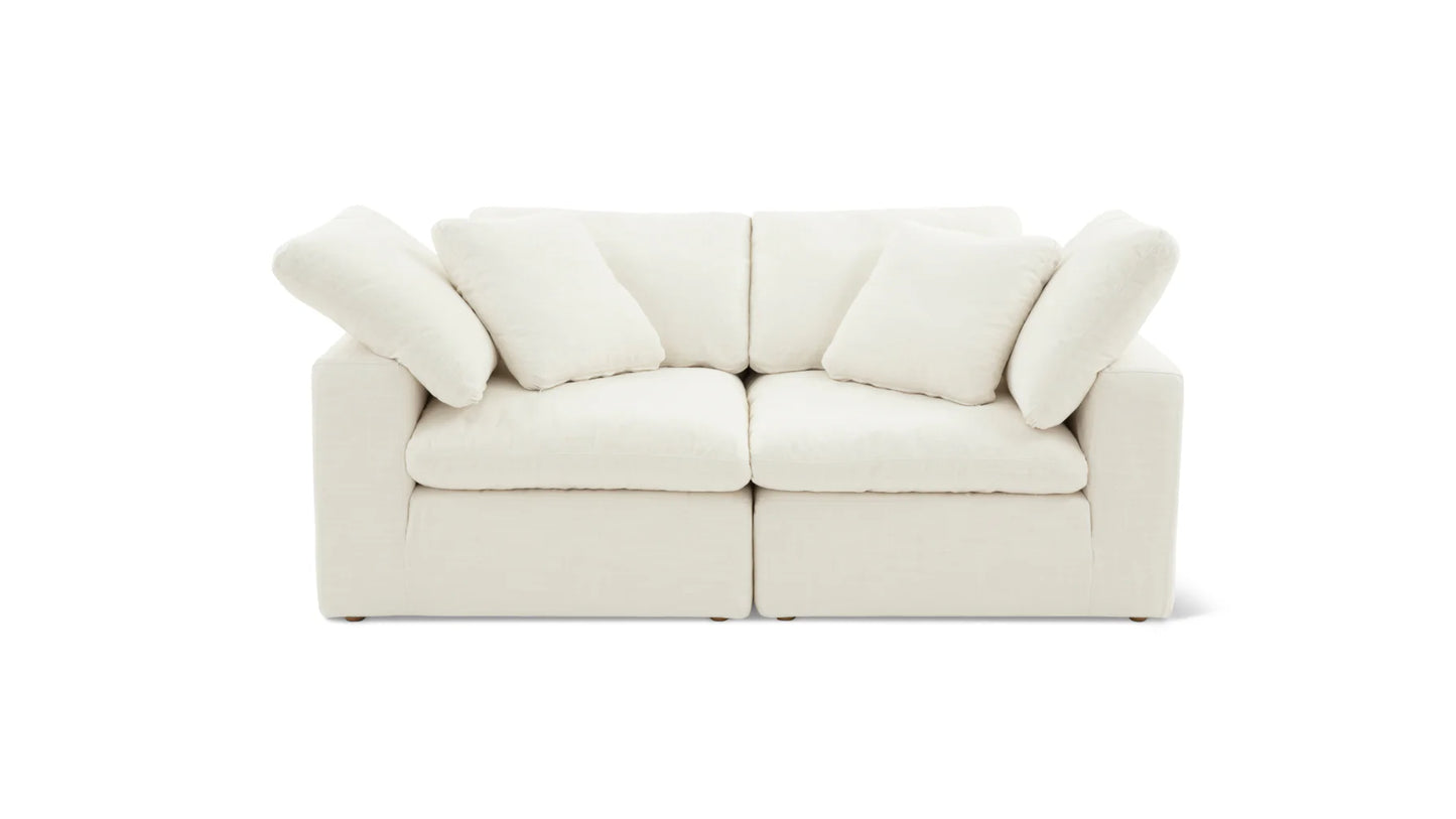 The Movie Night 3-Piece Modular Sofa is a modern, plush off-white seating option adorned with thick cushions against a plain white background. It includes four matching pillows, creating a cozy and minimalist design.