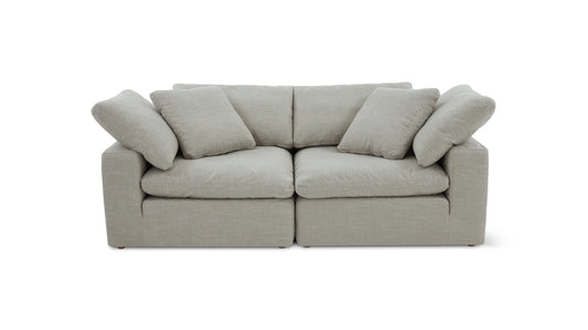 The Movie Night 3-Piece Modular Sofa is a light gray, modern piece with thick, cushioned seats and backrests, highlighted by four plush pillows. It is centered against a white background and showcases a minimalist design with clean lines, appearing highly comfortable.