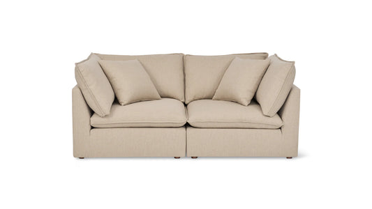 A Chill Time 4-Piece Modular Sectional, featuring a beige color with two large seat cushions and a backrest, is displayed against a white background, complete with four matching throw pillows. The sofa boasts a modern and minimalist design.