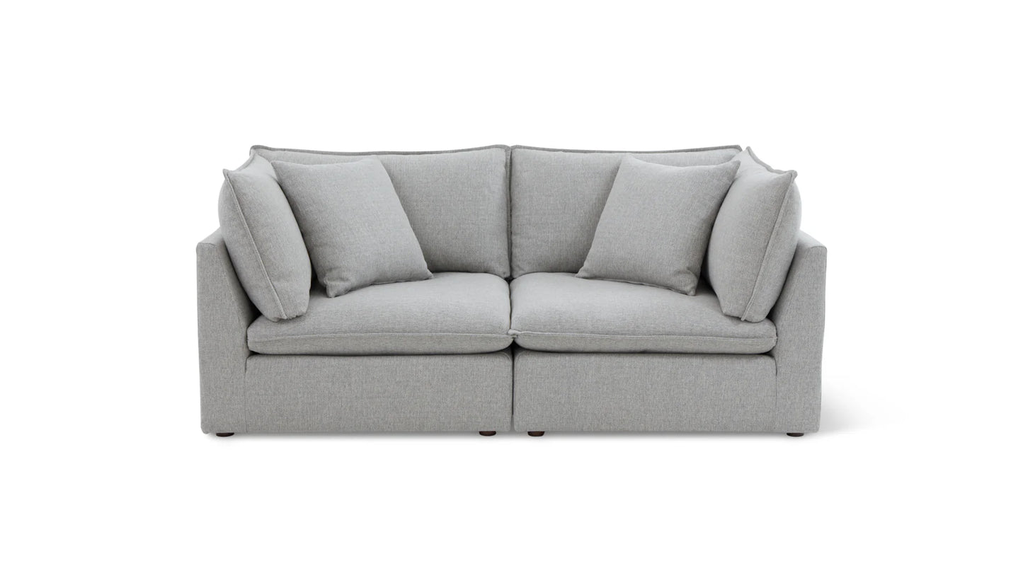 The Chill Time 4-Piece Modular Sectional is a modern gray sofa with a minimalist design, featuring two seat cushions and four plush back cushions. Set against a plain white background, it highlights the sectional's clean lines and soft texture.