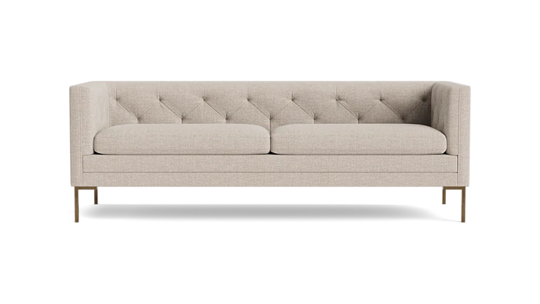 The Sit Tight 90" Sofa, featuring a beige tufted design with two cushions, is showcased against a solid black backdrop. Its minimalist aesthetic and wooden legs blend elegance with simplicity.