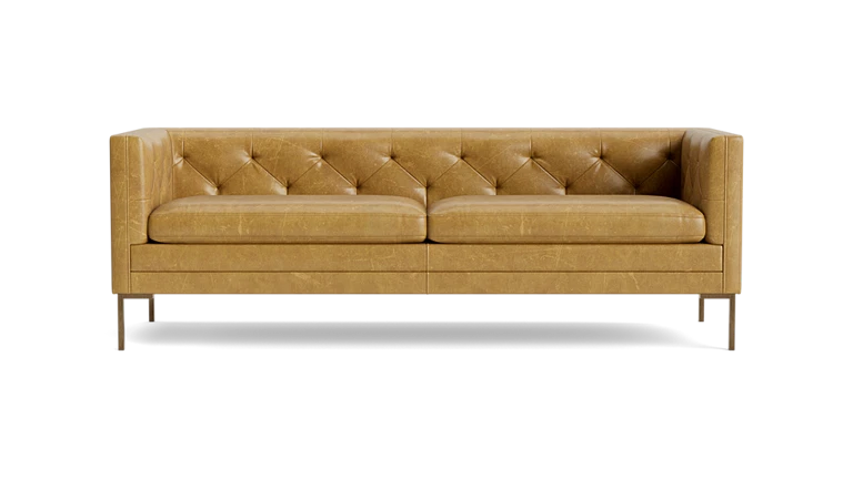 The Sit Tight 90" Sofa in tan leather showcases a tufted backrest and seat cushions. Its minimalist design is highlighted by clean lines and sturdy metal legs, set against a solid black backdrop.