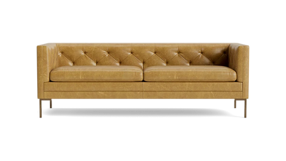 The Sit Tight 90" Sofa in tan leather showcases a tufted backrest and seat cushions. Its minimalist design is highlighted by clean lines and sturdy metal legs, set against a solid black backdrop.