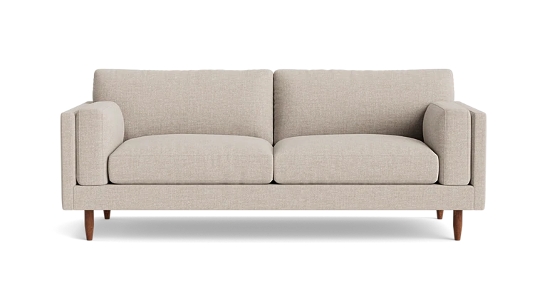 Introducing the "Skinny Fat 85" Sofa Standard Depth": A beige, modern sofa featuring two large cushions and wooden legs, elegantly set against a plain background. This minimalist masterpiece offers a cozy and stylish seating experience.