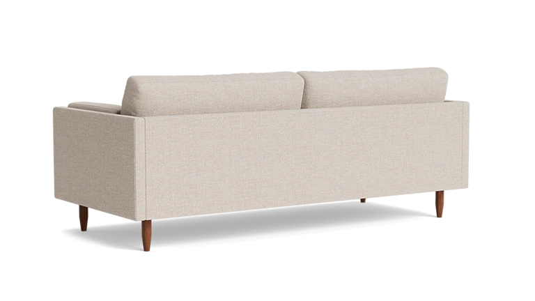 The Skinny Fat 85" Sofa Standard Depth is displayed from the back, showcasing its minimalist design with two plush cushions and wooden legs, all set against a plain black background.