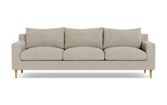 The Sloan Custom 3-Seat 95" Sofa, featuring a beige upholstery, square cushions, and wooden legs, is set against a plain black background. Its simple and modern design includes a straight back with armrests aligned at the same height as the back cushions.