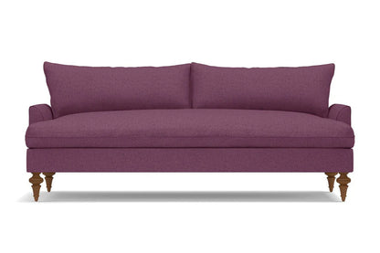 The Saxon Sofa is a modern piece in purple, featuring wooden legs and a sleek, minimalist design with a cushioned backrest. Its smooth fabric texture makes it an ideal choice for a contemporary living room setting.