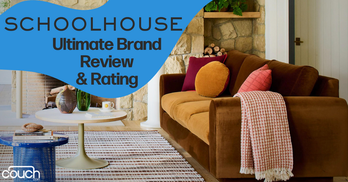 A cozy living room setup featuring a brown sofa with mustard and pink cushions against a stone wall. A white coffee table with decor sits on a striped rug. Large blue text reads, "Schoolhouse Ultimate Brand Review & Rating." The bottom left corner shows a "Couch" logo.