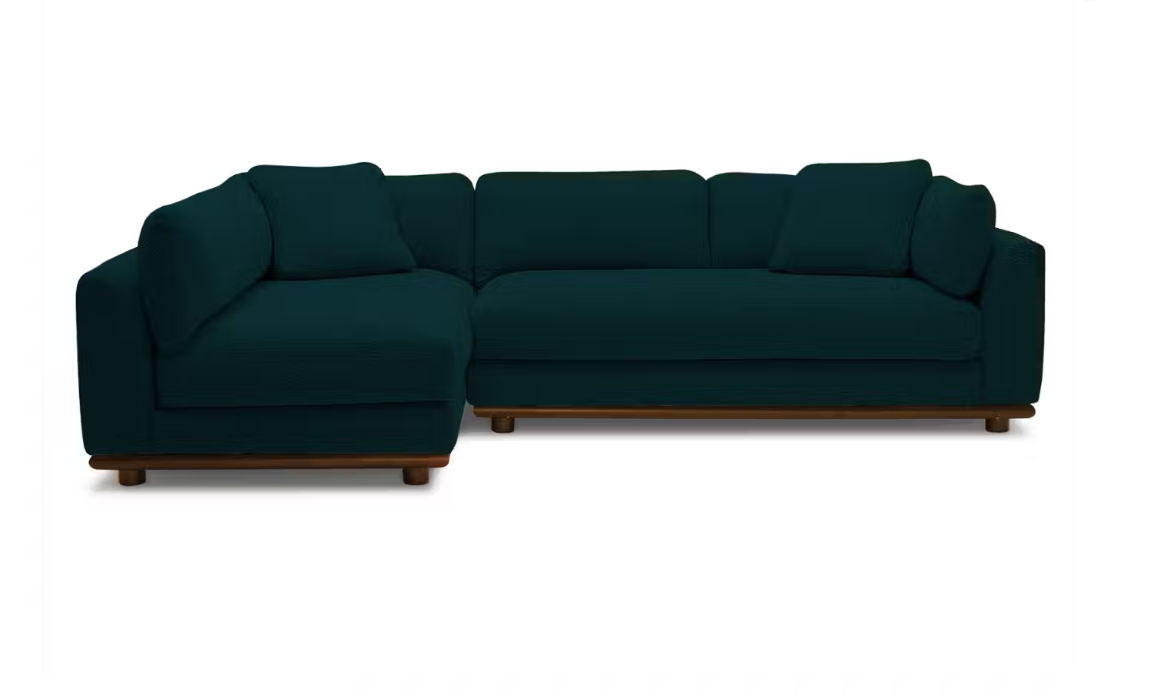 The Miller Sectional is a dark green sofa featuring plush cushions and a wooden base, arranged against a plain white background. This sectional boasts a modern design with an L-shaped configuration, making it ideal for a living room setting.