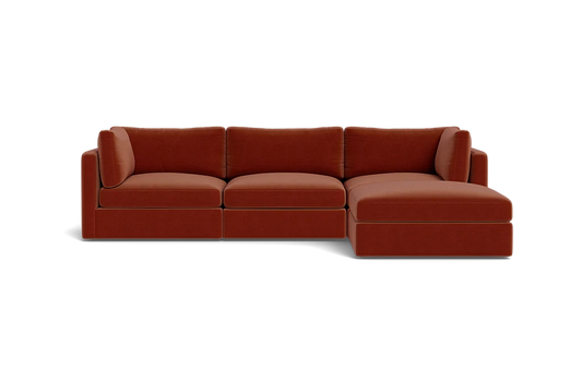 A contemporary Tatum Modular 3 Seat Chaise 106" Sectional showcasing clean lines, adorned with deep orange cushions, set against a simple black backdrop, and offering plush seating.