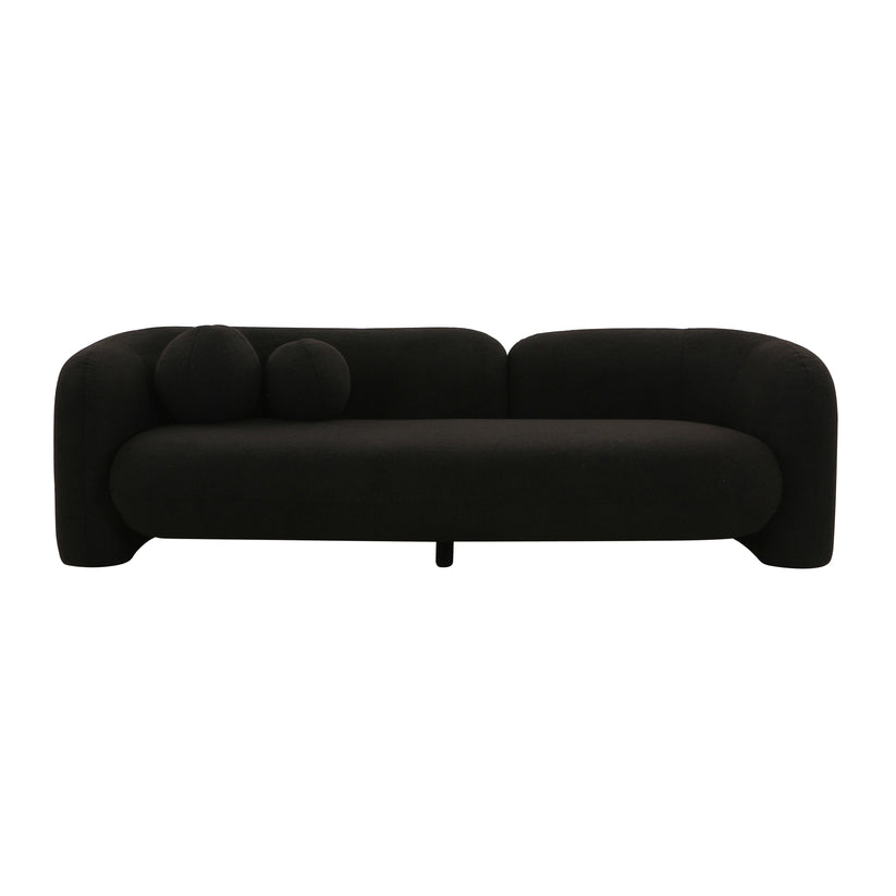 The Amelie Faux Fur Sofa is a sleek, modern seating option featuring a curved, minimalist design. It boasts two spherical black cushions on one side and a low, continuous backrest, creating a stylish and contemporary look.