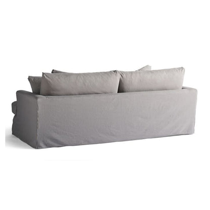 The Ava Slipcovered Sofa showcases a gray upholstery with a simple, modern design. It features a clean rectangular shape and is complemented by several large, cushioned back pillows. The fabric appears soft with a slightly textured finish. The image is set against a plain white background.