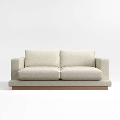 The Tidal Apartment 83" Sofa is a contemporary two-seater in beige, featuring plush cushions and a wooden base, presented against a simple light background.