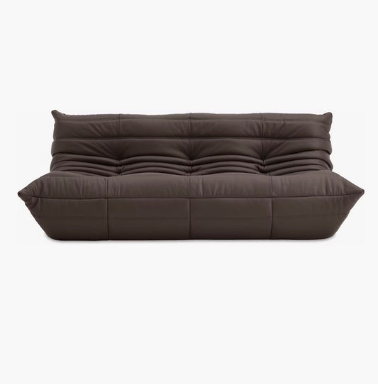 A sophisticated Togo Sofa in Opera Leather, featuring a dark brown color with a tufted and cushioned design and modern, angular armrests, set against a white background.