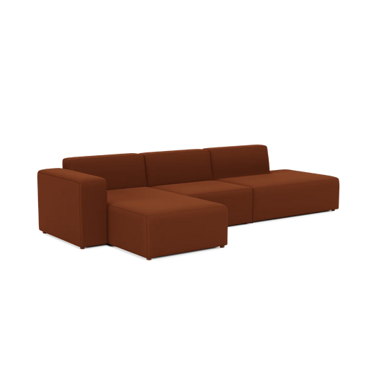 A modern Three-Seater Form Sectional in a rich, earthy brown, designed with a minimalist touch. This sofa highlights clean lines and blocky cushions, and includes an extended chaise lounge section on one side.