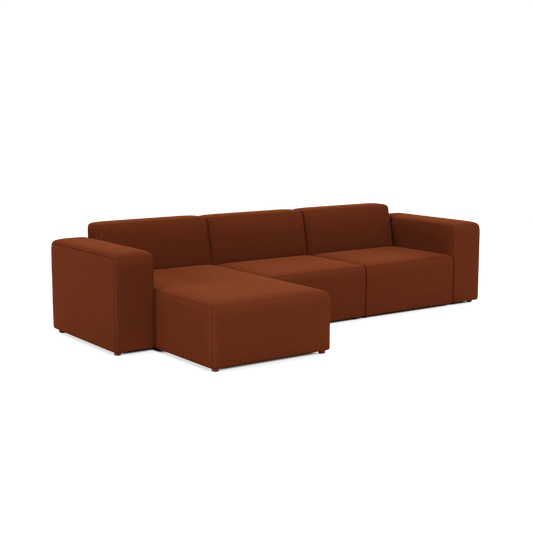 The Three-Seater Form Sectional is a modular brown sofa that includes three seats and a left-side chaise lounge. It boasts simple lines and blocky cushions, lending it a modern and minimalist aesthetic.