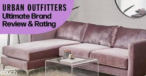 Image of a stylish living room featuring a pink velvet sectional sofa placed against a white wall with a round mirror above. A clear glass coffee table is positioned in front of the sofa. The text "Urban Outfitters Ultimate Brand Review & Rating" is displayed in the upper left corner.