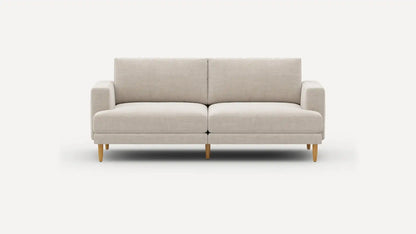 The Ember Mid-Century Modern 75" Sofa, featuring a sleek beige design and wooden legs, is showcased against a plain white background. It boasts a minimalist style with cushioned seats and armrests.