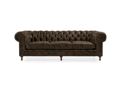 The Wessex Leather Sofa is a dark brown, tufted Chesterfield with elegant rolled arms and three seat cushions, showcased against a plain white background. It features a classic design complemented by wooden feet.