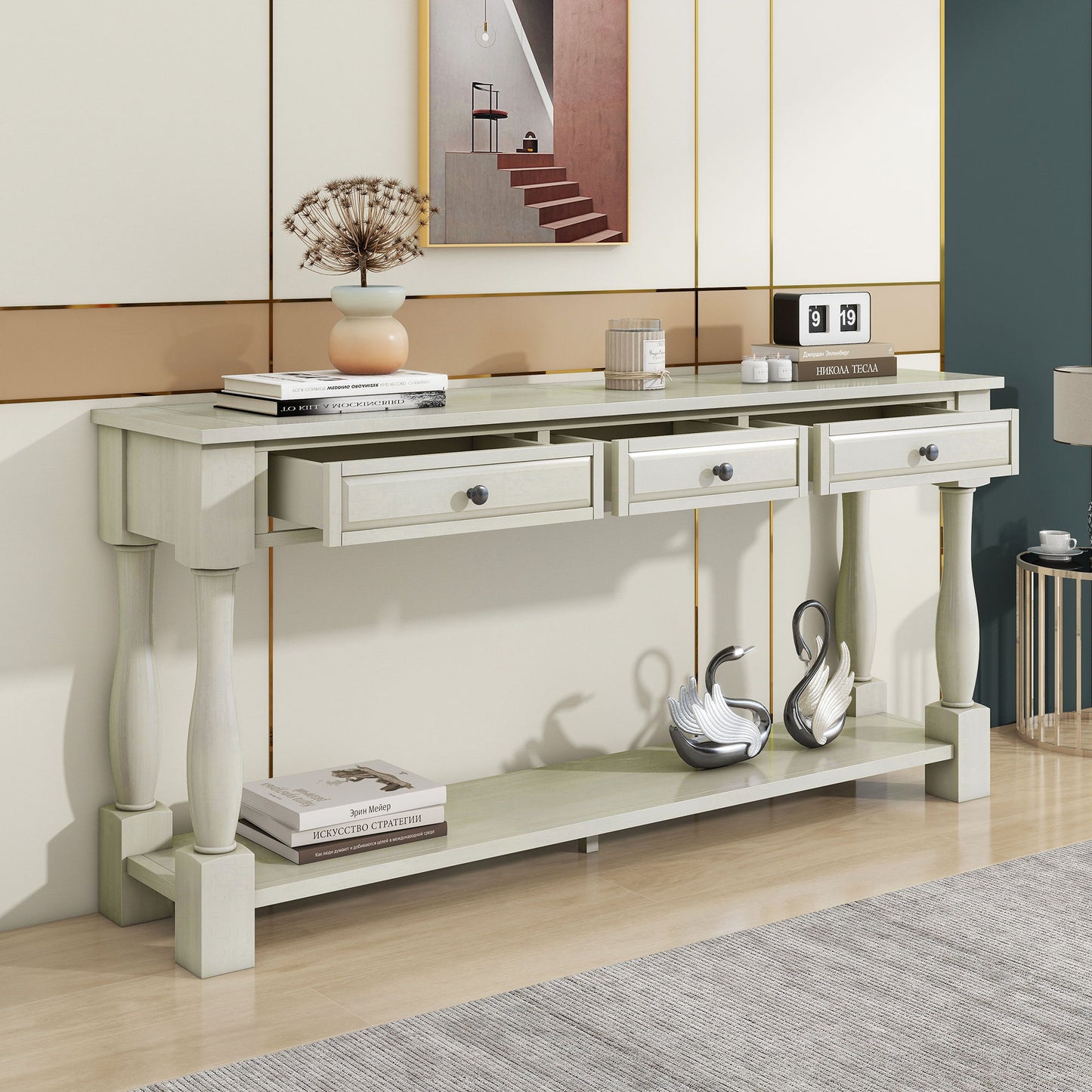 The Console Table Long Console Table with Drawers and Shelf for Entryway, Hallway, Living Room features three elegant drawers. It's topped with decor like a floral vase and framed picture, while the lower shelf displays two swan figurines against a modern wall and light wood flooring.