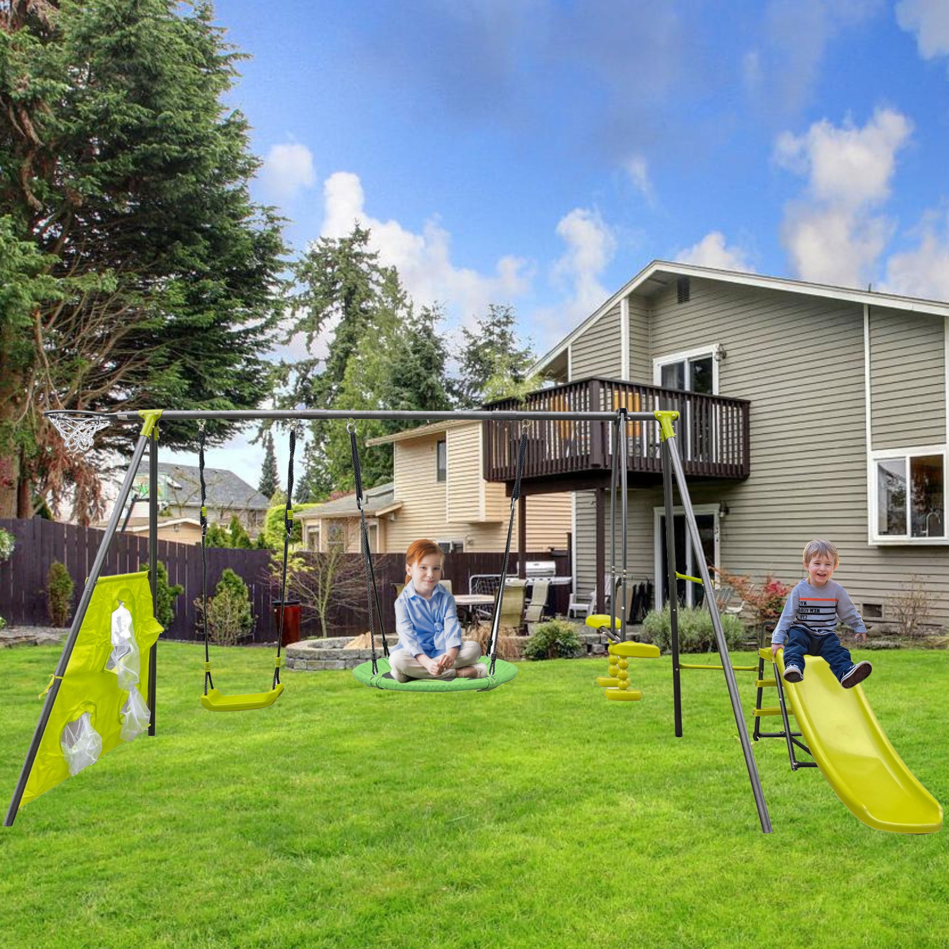 Two kids enjoy the Interesting Six Function Swingset on a green lawn; one swings on the 31.5" net swing, while the other sits on the slide. A house with a deck and trees under a partly cloudy sky completes this serene backyard scene.