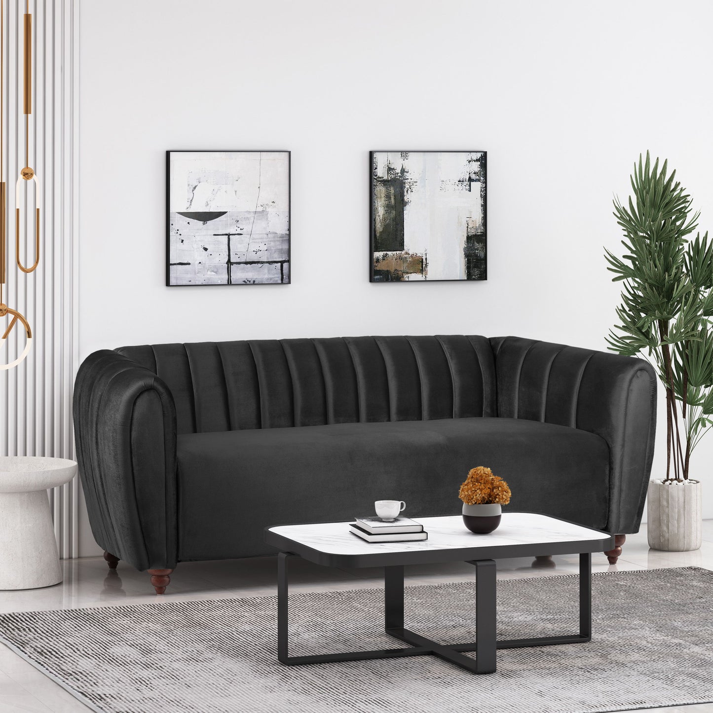 A modern living room features a 3 Seater Sofa Modern Glam Design in black velvet, abstract wall art, and a white coffee table holding a small plant and cup. A tall green plant stands in the corner, complementing the neutral tones and minimalist decor.