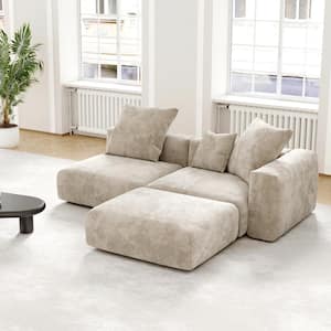 A stylish living room showcasing a black sectional sofa, made of corduroy polyester, with large cushions. The room is illuminated by natural light streaming through white-framed windows. A nearby black, round coffee table complements the setting, while a green plant adds a touch of nature in the corner.