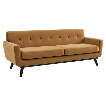 A contemporary, cognac-colored, velvet three-seater sofa with a tufted design and black legs. This sofa showcases a mid-century aesthetic with square arms and two spacious seat cushions.