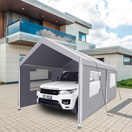 A white Range Rover is parked under a gray 10x20 Heavy Duty Portable Carport Garage Tent for Outdoor Storage Shelter on a paved driveway. The carport is in front of a modern, multi-story house with large windows and a balcony, beneath a partly cloudy sky.