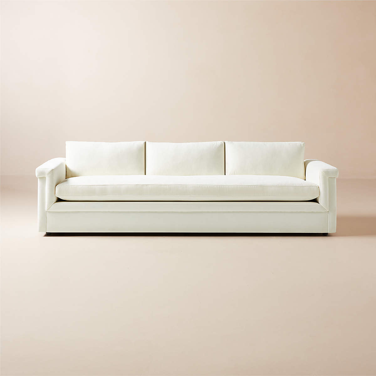 A contemporary, minimalist light blue Ceva 103" Performance Velvet Sofa with three cushions placed against a pale-colored wall. The sofa boasts sleek armrests, featuring a simple and elegant design that cultivates a sophisticated and cozy atmosphere.