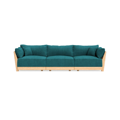 The Modular Bondi Latte 3 Seater Sofa is a modern and symmetrical teal sofa with wooden armrests and a wooden base. It includes three large seat cushions and several matching back cushions, all designed with clean lines.