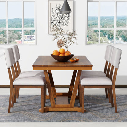 A modern dining room features the Topmax 5 Piece Rustic Dining Table Set, including a rectangular wooden table and four upholstered chairs. A bowl of oranges and a decorative branch sit on top. Large windows reveal greenery and rooftops, while a pendant light hangs above.