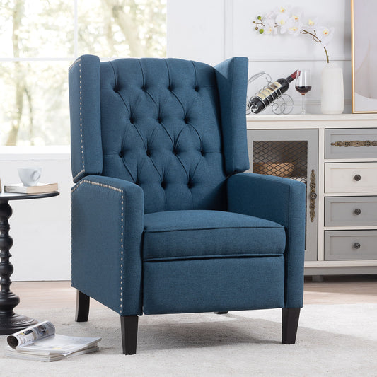 The Manual Wing Chair Recliner, with a tufted backrest, silver nailhead trim, and dark wooden legs, is set in a bright room beside a side table and white decor cabinet. A large window lets in natural light.