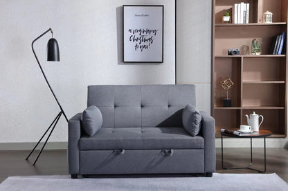 A modern living room showcases a gray 2-seater sleeper sofa bed with two cushions, a black floor lamp, and a round wooden side table holding a teapot and cups. A bookshelf and framed quote rest on the wall behind the convertible loveseat with a side pocket.