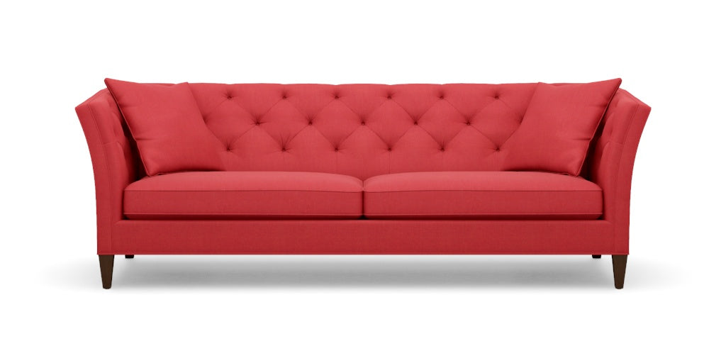 Introducing the Shelton 98" Sofa: a contemporary red sofa featuring a tufted backrest and two seat cushions. It showcases angled armrests, rests on four dark wooden legs, and comes complete with two coordinating red throw pillows at each end.