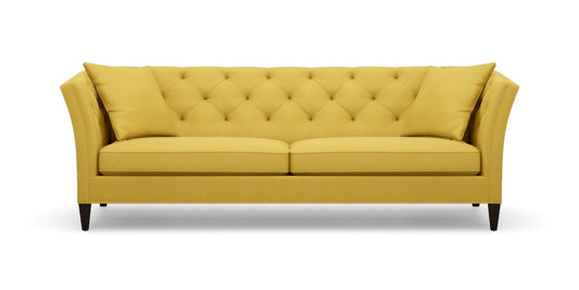 The Shelton 98" Sofa features a tufted backrest and two seat cushions in a mustard yellow color. It is designed with flair arms and rests on dark wooden legs.