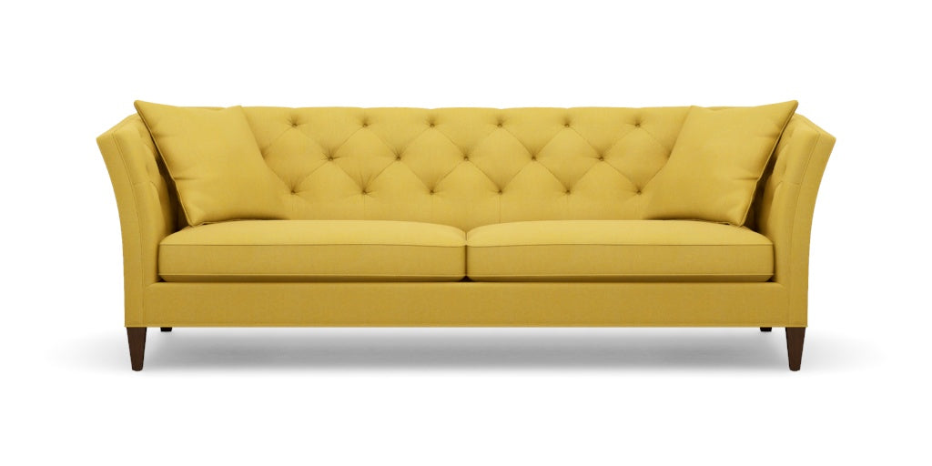 The Shelton 98" Sofa features a mustard yellow tufted design with two seat cushions and two back cushions. It has high arms and dark wooden legs, all set against a plain white background.