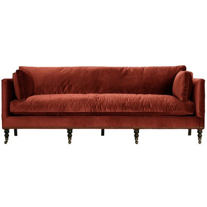 The Margot Velvet Sofa features a plush, rich red velvet upholstery and includes decorative round cushions on each end. With its low back and six dark, turned wooden legs, this sofa showcases a classic and elegant design.