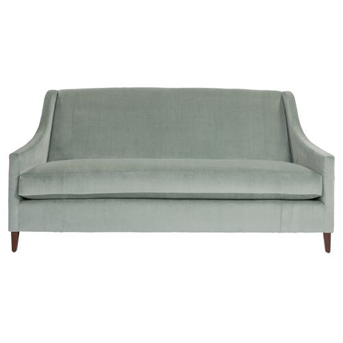 Introducing the Dawes Sofa in Sage Velvet, featuring a minimalist design with elegant wooden legs. The sofa boasts a smooth, curved backrest and armrests, offering a sleek and modern aesthetic.