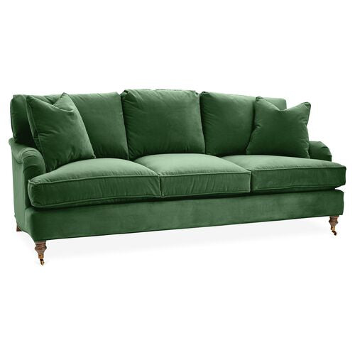 The Brooke 6-Seat Sofa is a plush, green velvet piece with six seat cushions and large back cushions. It features elegant wooden legs with caster wheels, providing a classic and sophisticated look.