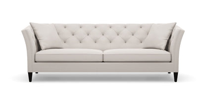 The Shelton 98" Sofa features a sleek and modern design with a beige tufted finish, two seat cushions, and angled arms. It is supported by dark wooden legs and comes with two matching throw pillows on each end, all set against a plain white background.