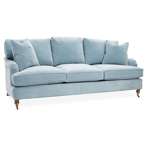 The Brooke 6-Seat Sofa comes in a light blue color, featuring plush cushions and dark wooden legs. It includes soft, cushioned armrests and two large back cushions, offering a cozy and inviting appearance.